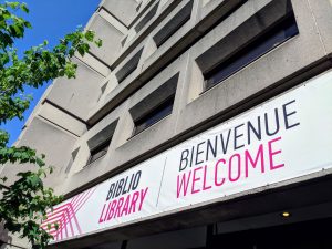 Banner above McLennan Library Building reads: Biblio/Library, Bienvenue, Welcome