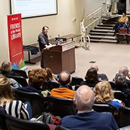 Jonathan Goad lecturing from podium with view of crowd in foreground