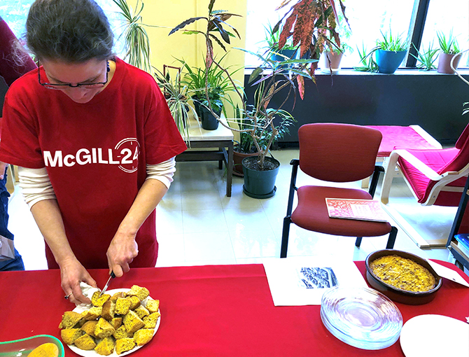 A Library staff member cutting pastries while wearing a McGill24 t-shirt.