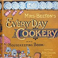 Close up of gold cover of "Mrs. Beeton's Everyday Cookery and Housekeeping Book"