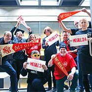 Group of Library staff members holding up McGill flags and signs that say "#McGill24"