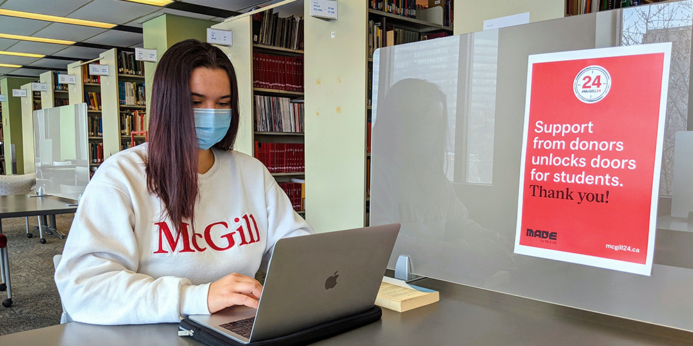 A student at a desk in the Study Hub wearing a mask.