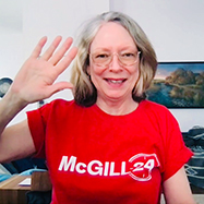 Dean Colleen Cook over Zoom in a red McGill24 t-shirt smiling and waving.