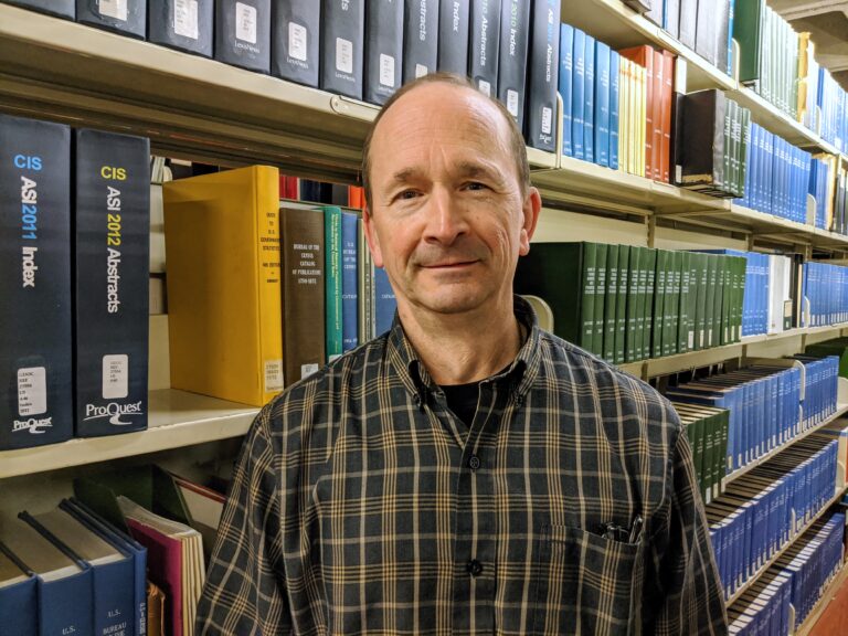 Steve Blaise in front of bookshelves.