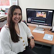 Alisa Nosova sitting at a desk, smiling at the camera.