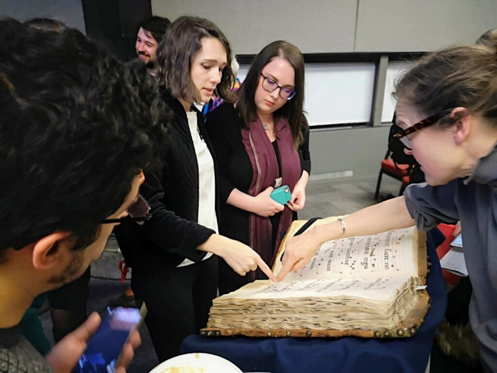 A small group surrounding a manuscript.