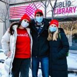 Students wearing masks and red McGill24 hats standing in front of the Library.
