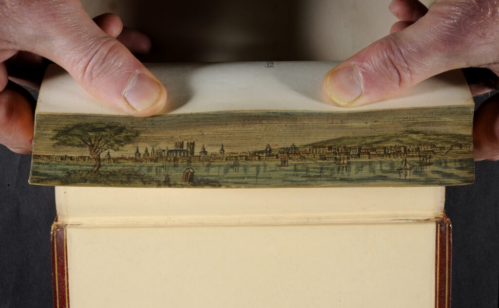 a fanned fore-edge painting held by two thumbs