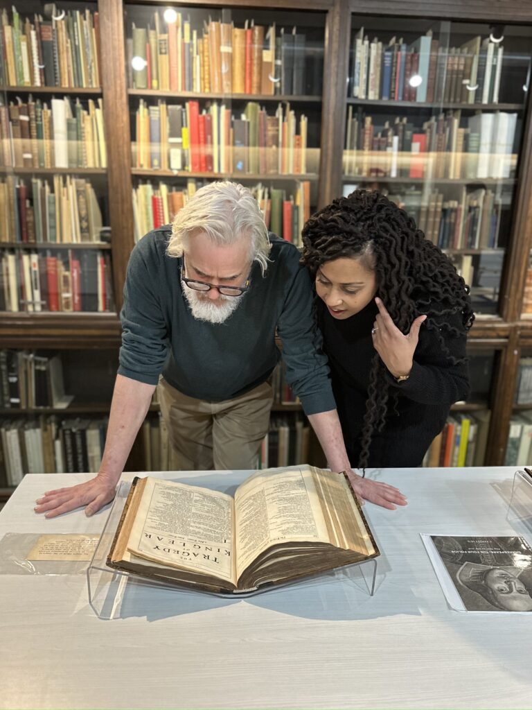 Paul Gross and Kimberley Rampersad looking at rare books with bookshelves behind them.