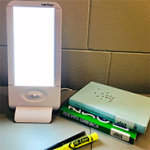 Light therapy lamp on desk surrounded by books and pens.