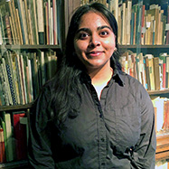 Mashall Hameed smiling at the camera, standing in front of bookshelves.