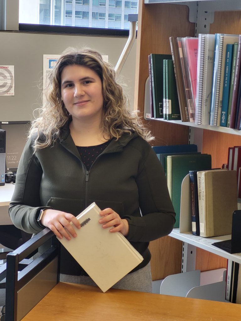 Sophie Cohen next to a bookshelf in the Marvin Duchow Music Library