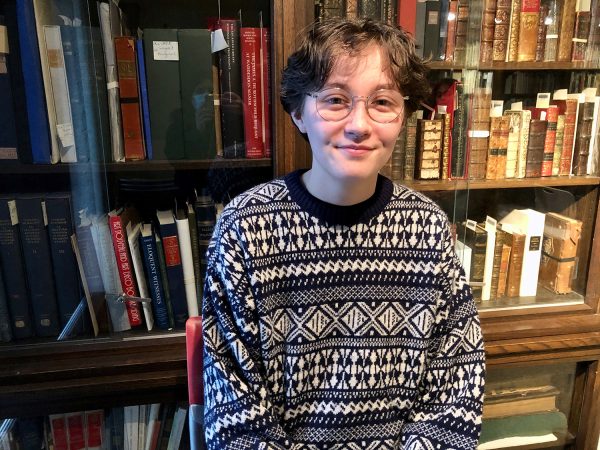 Katie Carleton smiling at the camera in front of a bookshelf.