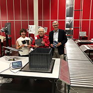 From left to right: Lenore Harris, Louise Robertson, and Don Walcot at the McGill University Collections Centre holding up books in front of red wall.