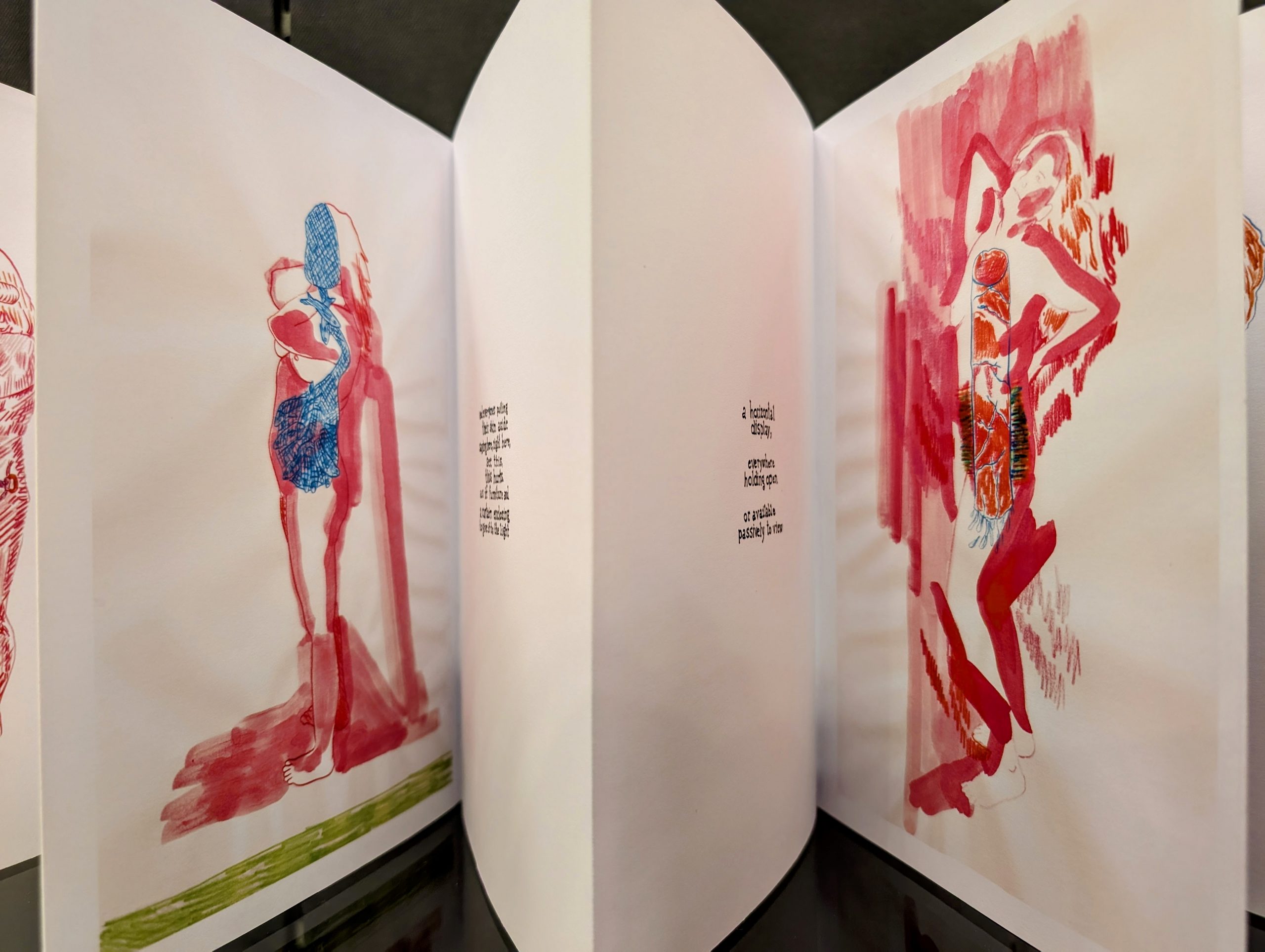 Folded artwork on a long piece of white paper featuring illustrations of bodies alongside text.