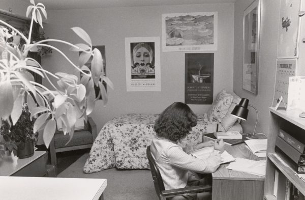 Black and white photo of student studying in dorm room in 1970s.